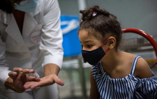 Una enfermera muestra a una niña un vial con la vacuna cubana antiCOVID-19, Soberana 02, agosto de 2021. Foto: Tomada de The Washington Post.